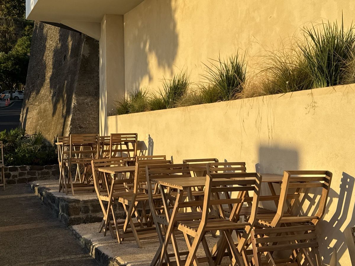 Folding wooden chairs and tables against a sunlit wall at Obsidian 17